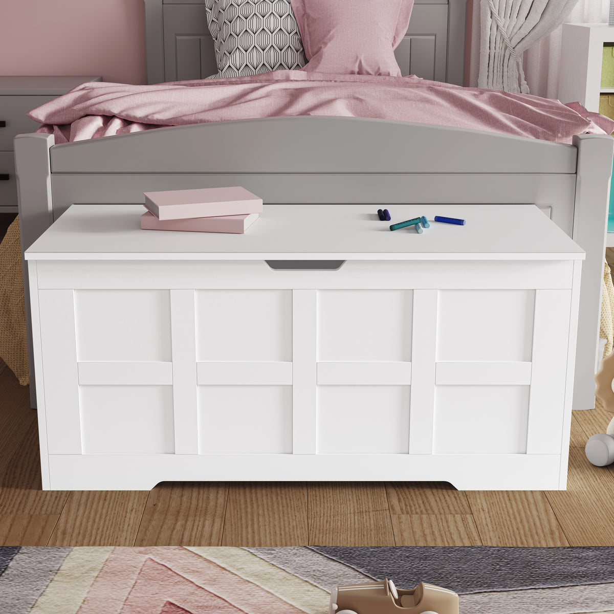 [White] White shaker toy storage box with grid panel front and cutout handle at foot of pink-bedded bed