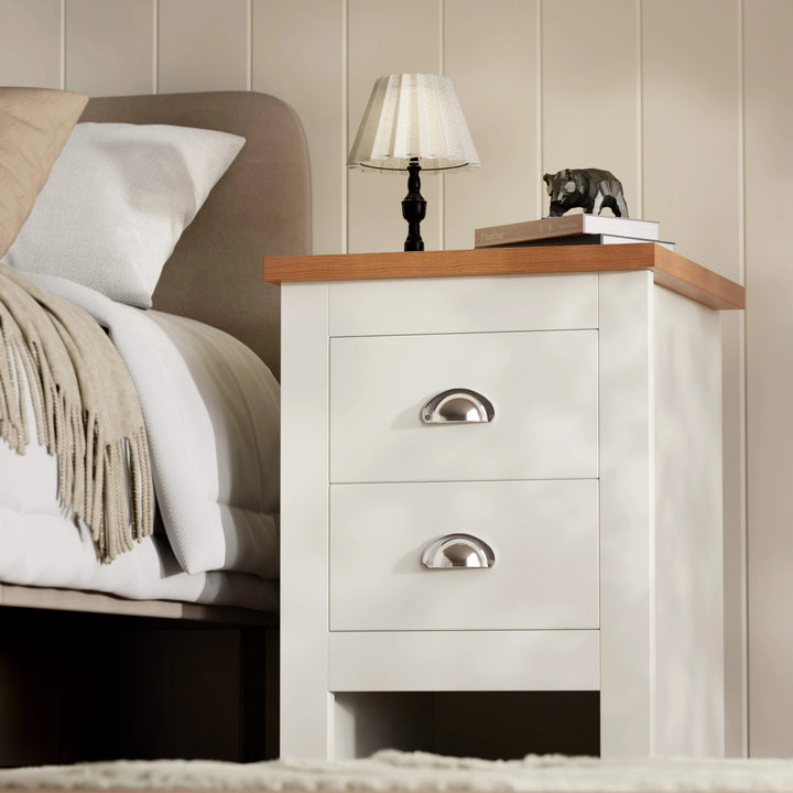 [White] front view of white shaker bedside table, two drawers with chrome cup pulls, oak-effect tabletop