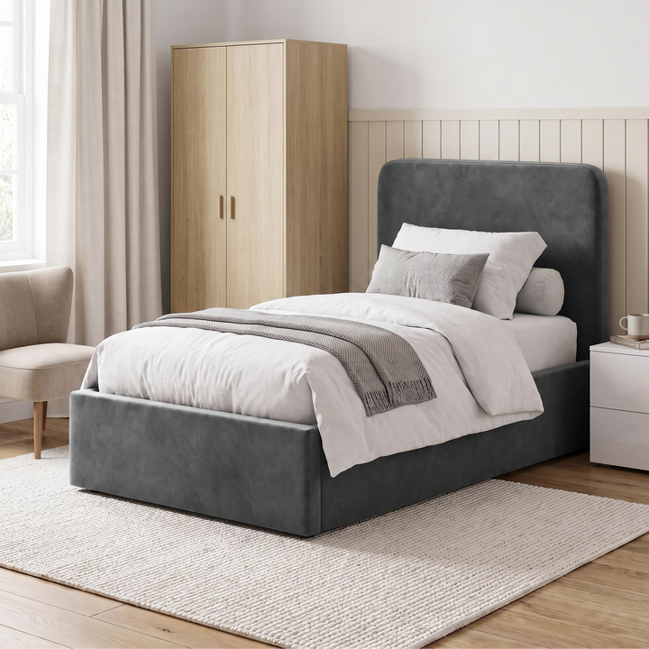 [Single | Grey] Angled bedroom view with plain rounded headboard, wardrobe, chair, bedside table, and window
