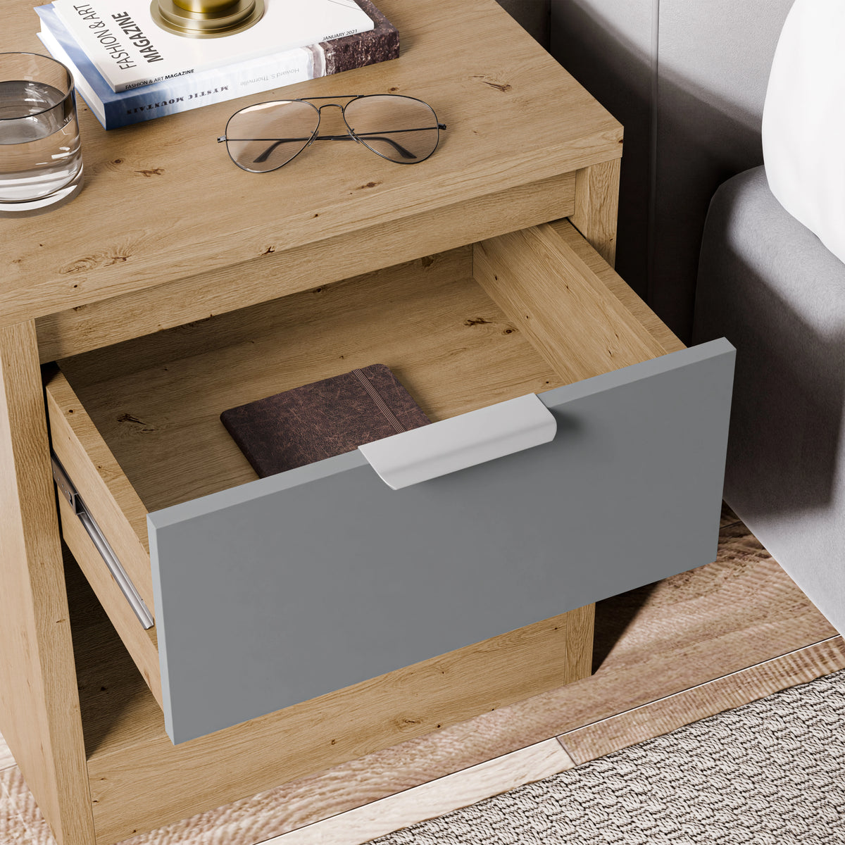 [Oak+Grey] Top-down detail of Skova bedside table with grey drawer fully out, oak surround and reading glasses on top