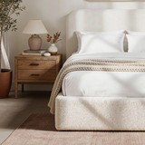 [White | King] Sofna boucle ottoman bed king side view, textured base with chunky knit throw and oak nightstand