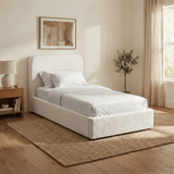 [White | Single] Sofna boucle ottoman bed angled in room, white boucle single frame with curved headboard on wooden floor