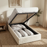 [White | Single] Boucle ottoman bed with gas lift raised from foot end, wooden slats and central iron support bar visible