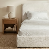 [White | Single] Sofna boucle ottoman bed from the side, white boucle side rail and puffed headboard beside a wooden bedside