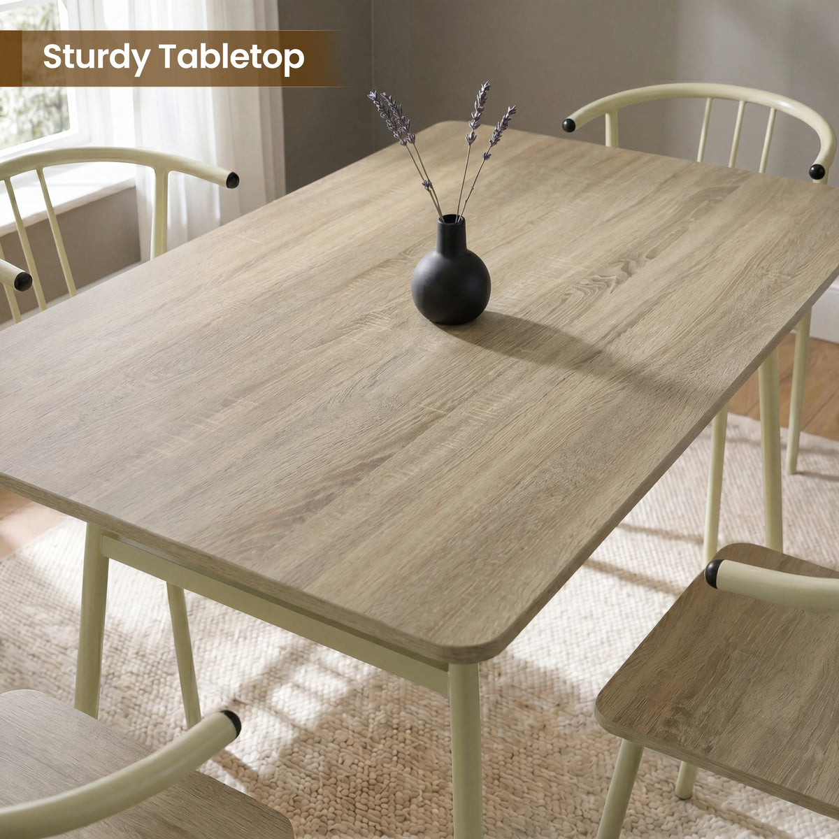 [Sonoma Oak] Torvi dining table and chairs overhead close-up showing oak-effect tabletop surface with a small vase and four cream metal arm chairs around it