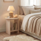 [Taupe] Small Round Side Table with Shelf Living Room used as bedside table beside neutral linen bed with ceramic lamp and candles on top and books on lower shelf