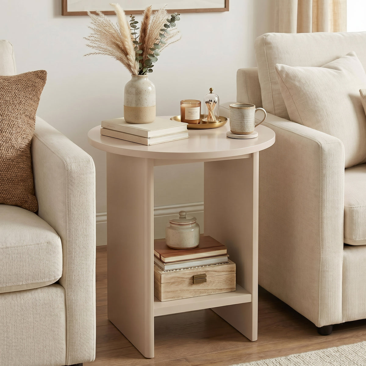 [Taupe] Small Round Side Table with Shelf Living Room positioned between two cream sofas with pampas vase on top and stacked books and wooden box on lower shelf