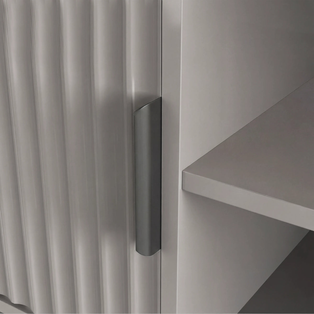 [Grey] Macro view of grey Flutrina TV cabinet door edge, ribbed panel and silver handle next to interior shelf