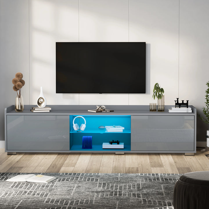 [Grey] TV stand unit in grey gloss with wall-mounted TV above and headphones plus console on lit shelf
