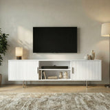 [White] White Flutrina TV cabinet at slight angle on cream rug, fluted side doors closed, central shelf in view.