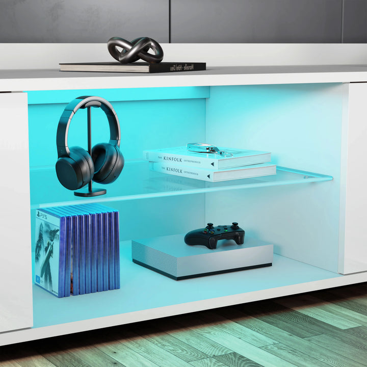[White] Close-up of white TV unit central shelves: headphones on stand, books stacked, console below