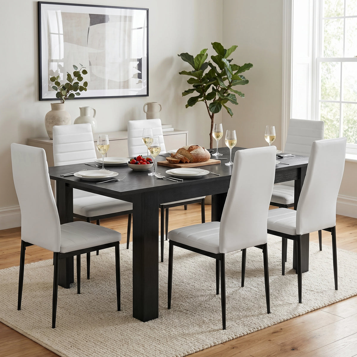 [Black Wood] Extended black wood-effect dining table for 6-8 with bread and wine; six white chairs surround its thick square legs.