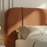 [Double | Orange] Headboard detail with warm rust upholstery and curved top edge against cream moulded wall