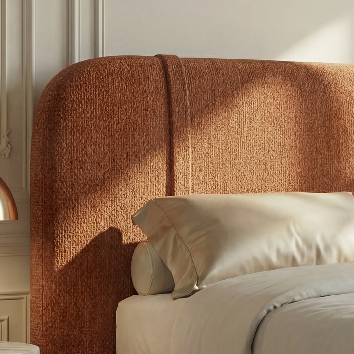 [Double | Orange] Headboard detail with warm rust upholstery and curved top edge against cream moulded wall