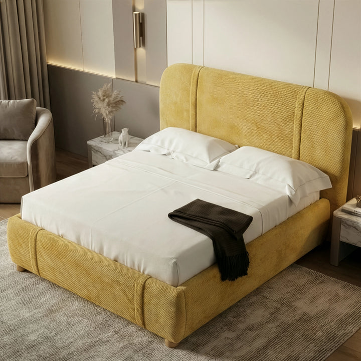 [King | Yellow] Raised perspective of mustard king fabric bed with rumpled white bedding and pampas vase on nightstand