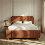 [King | Orange] Fabric bed frame from the front with white satin bedding and brass dome lamp on marble table in a bedroom