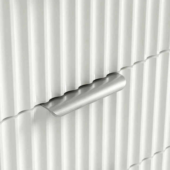 [White] Chest of drawers with silver metallic handles against a green wall placed in a natural light room