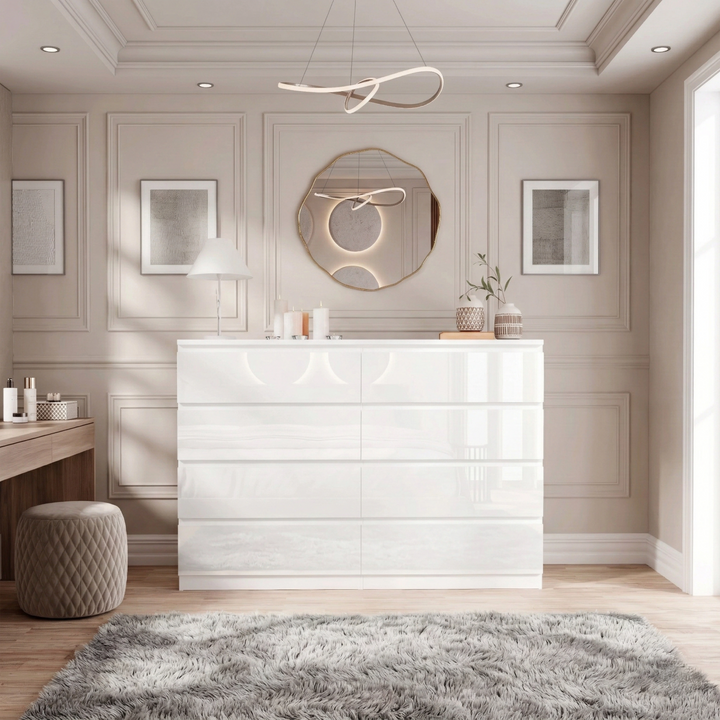 [White] high gloss wide chest of drawers centred under round gold mirror with grey rug and pouf beside