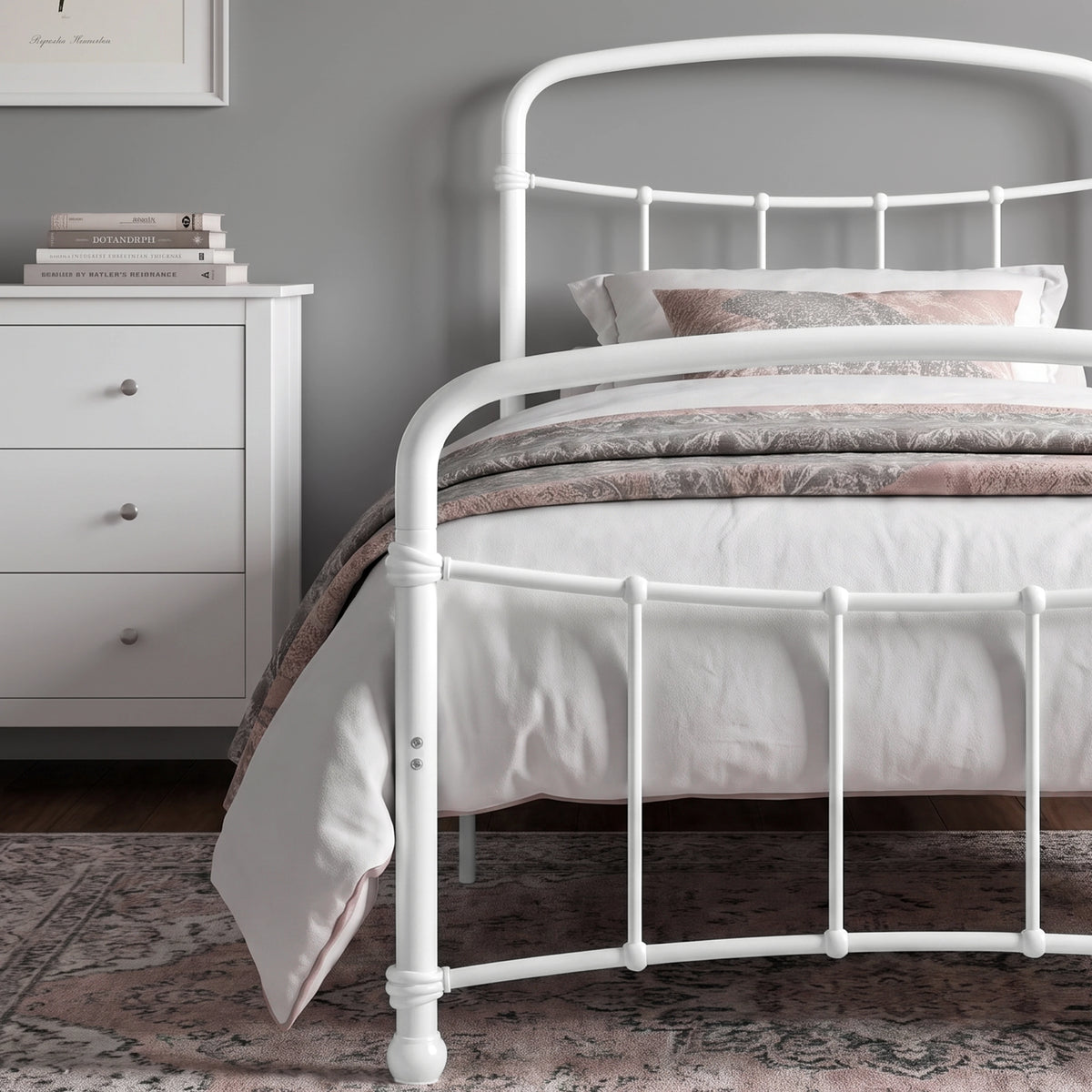 [White | Single] Close view of the white curved front rail, vertical bars and white bedding beside a drawers