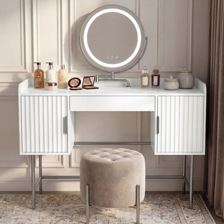 [White] dressing table with three drawers and a round mirror in flutrina design, placed against a wall in a softly lit room