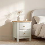 [White] nightstand with wooden top next to a bed in a bedroom setting