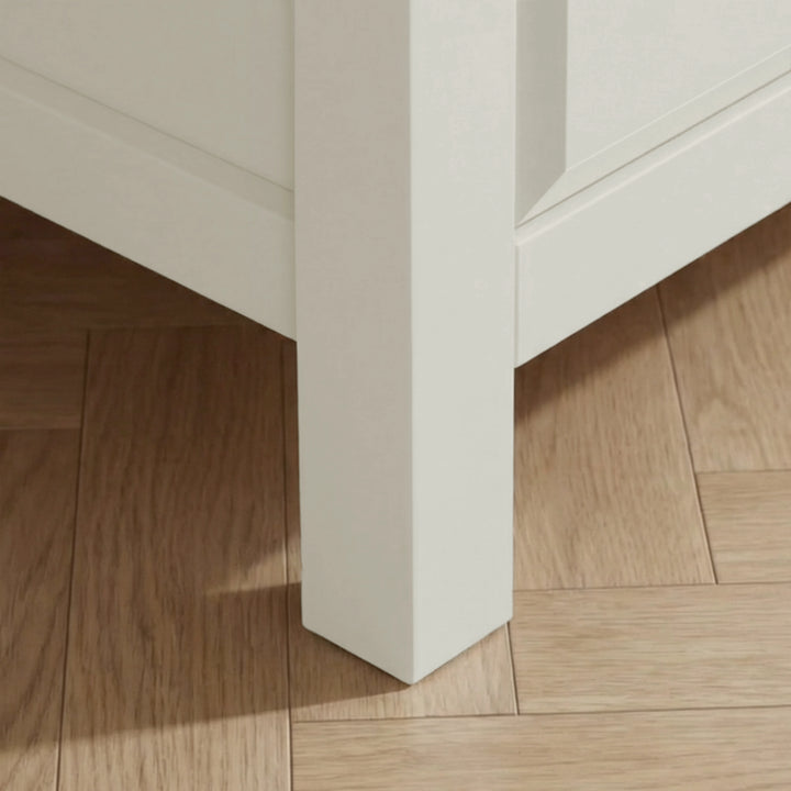 [White] Haven chest close-up of the solid square white painted leg resting on warm oak herringbone parquet flooring