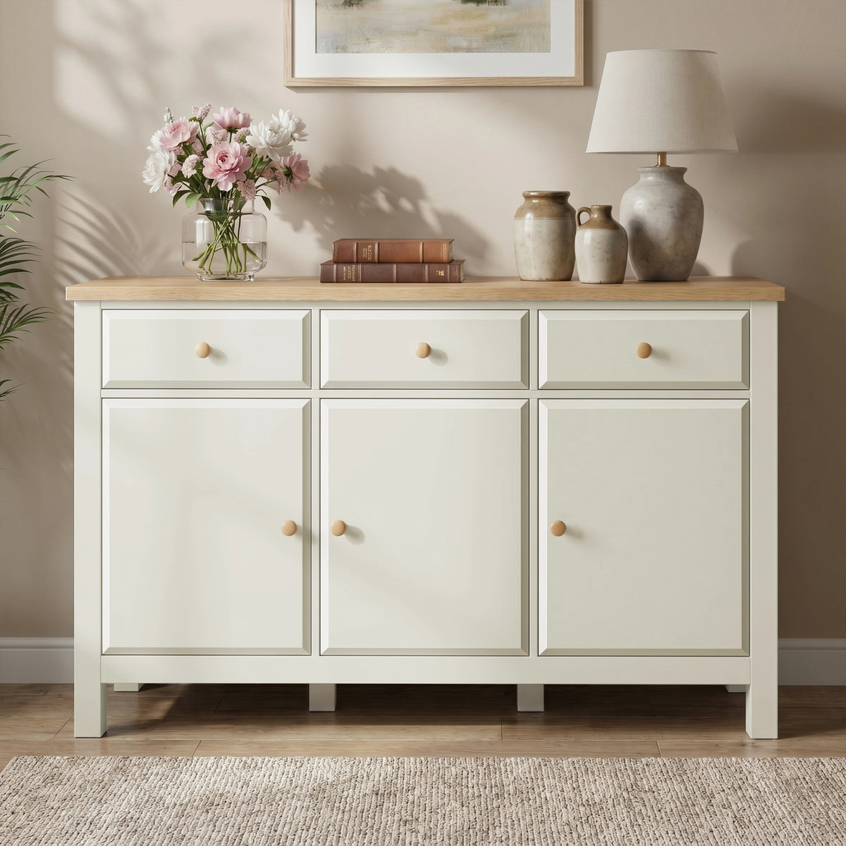 [White] Haven sideboard straight front view with oak top, framed doors, drawers, flowers, books, and vases.