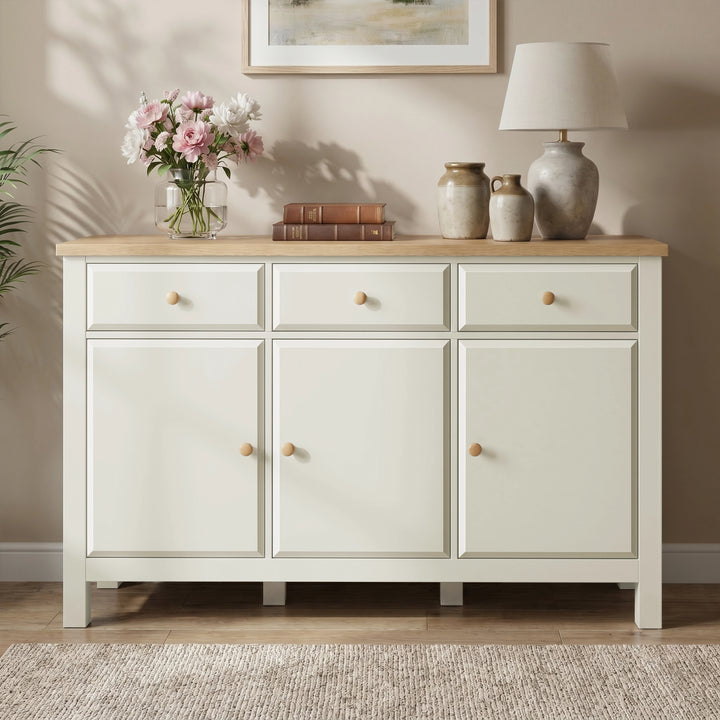 [White] Haven sideboard straight front view with oak top, framed doors, drawers, flowers, books, and vases.