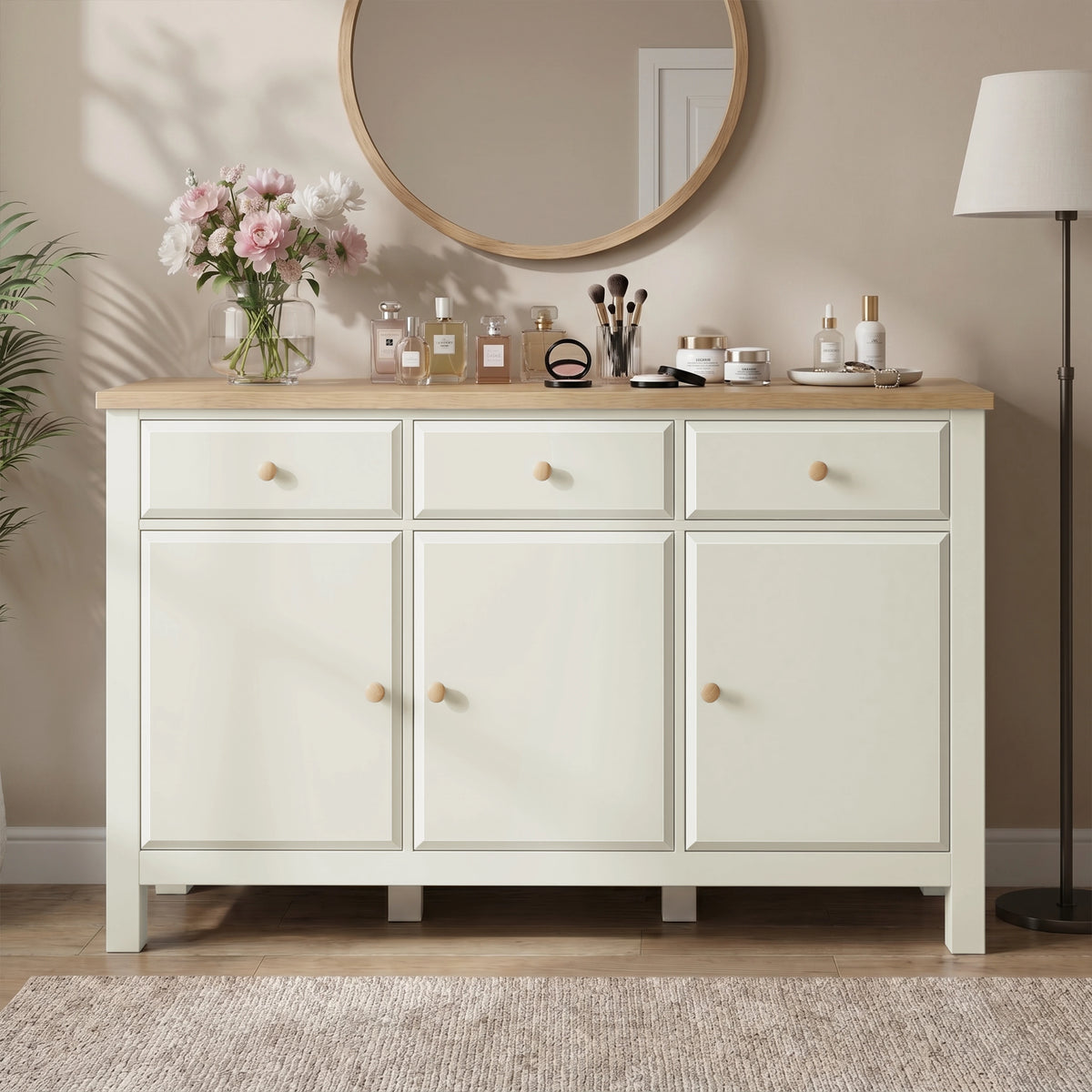 [White] Haven sideboard front view with oak top, framed doors, drawers, round mirror, flowers, lamp, and vases.