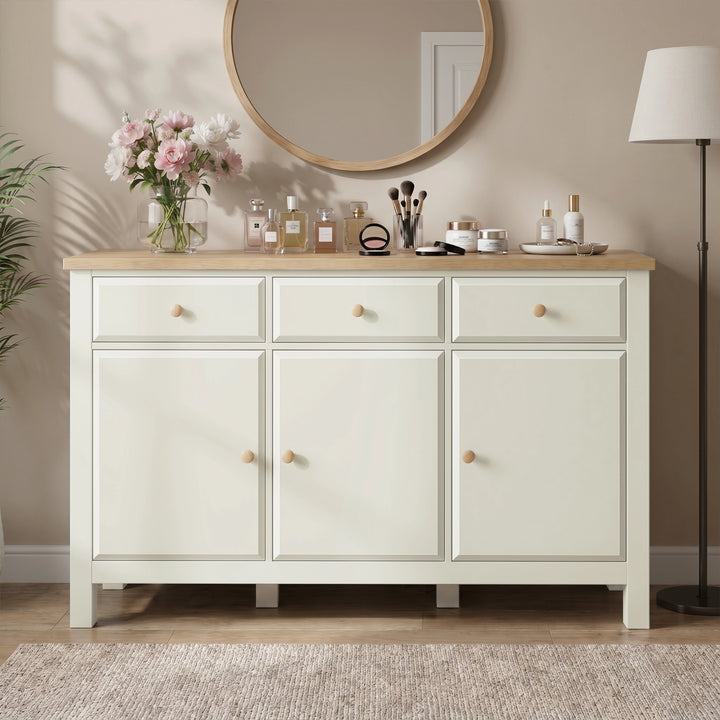 [White] Haven sideboard front view with oak top, framed doors, drawers, round mirror, flowers, lamp, and vases.