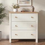 [White] dresser with wooden top in a room with a plant and framed picture