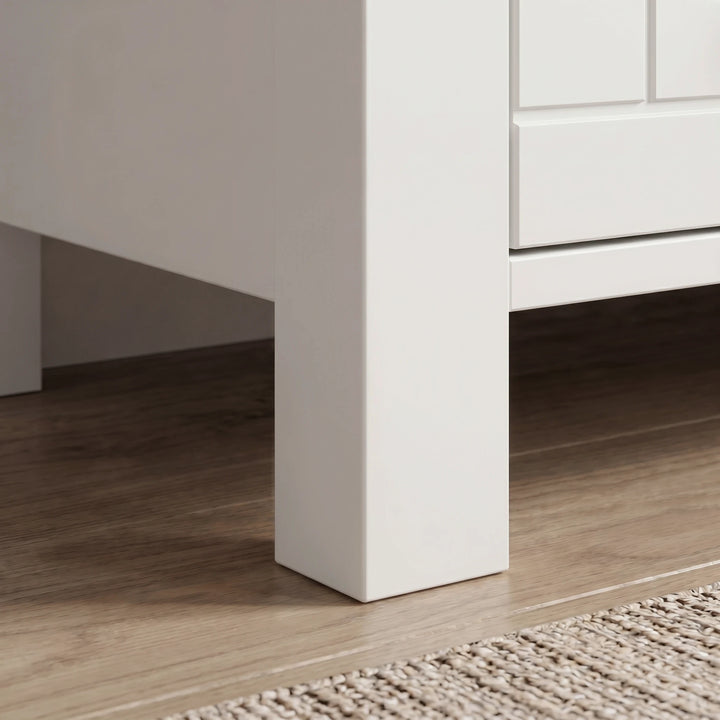 [White] Linra 4 drawer chest close-up of solid square painted leg construction and raised base clearance on dark hardwood flooring