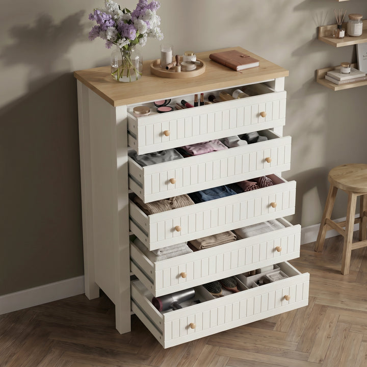 [White] Linra tall 5 drawer chest with all five drawers open at an angle showing stored folded clothing and accessories against dark wall