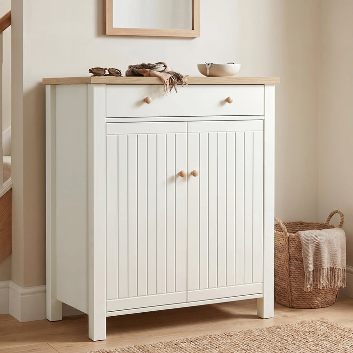 [White] Linra White 4 Tier Painted Shoe Storage Cabinet featuring a closed two-door slatted front design with a wooden top surface decorated with personal accessories in a bright hallway.