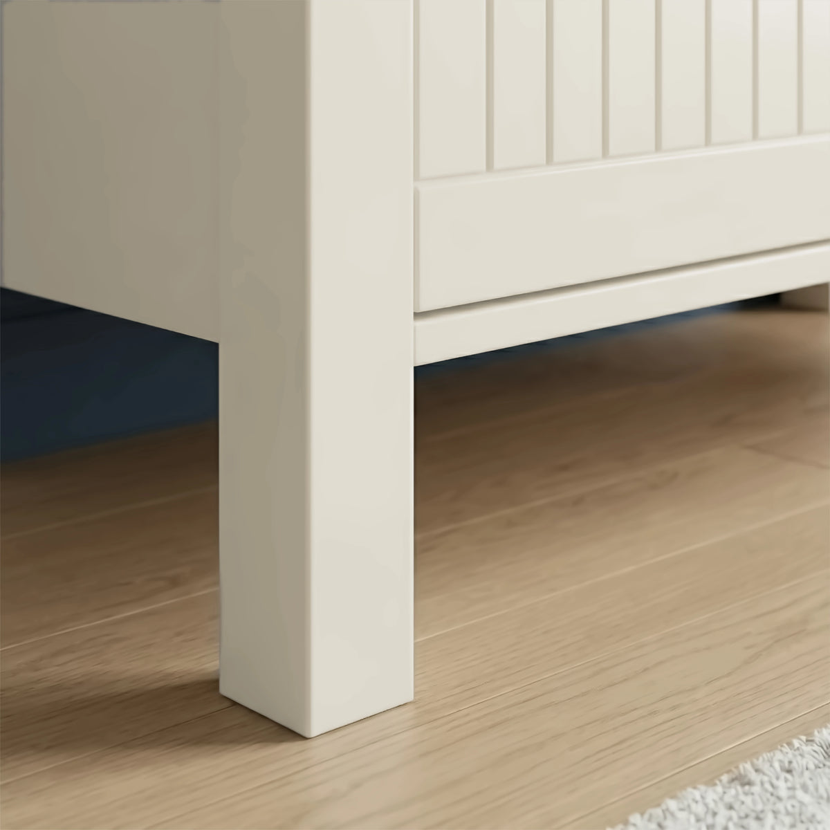 [White] Linra 3 door sideboard close-up of solid square leg construction and tongue-and-groove door panel detail on light oak flooring