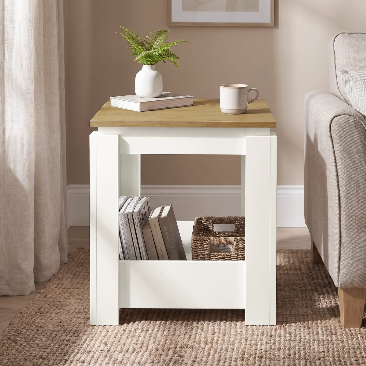 [White] Front view of the square side table beside a sofa, with books and a wicker basket stored below