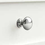 [White] Oskara TV unit macro close-up of a single polished metallic round drawer knob against a painted white shaker-style drawer front