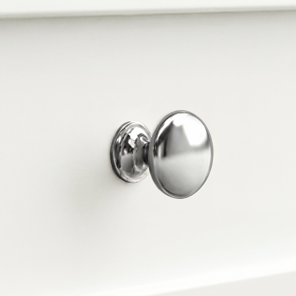 [White] Oskara TV unit macro close-up of a single polished metallic round drawer knob against a painted white shaker-style drawer front