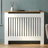 [Medium | White] Radiator Cover front view with oak top shelf holding a diffuser, tray, and book against a teal wall