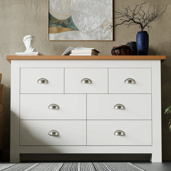 [White] Shaker 7 drawer wide chest with oak top cup handles and abstract art on textured wall.