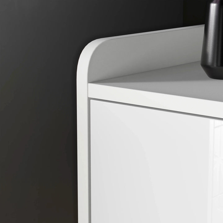 [White] edge view white TV unit highlighting curved tray-style top and gloss flap door below