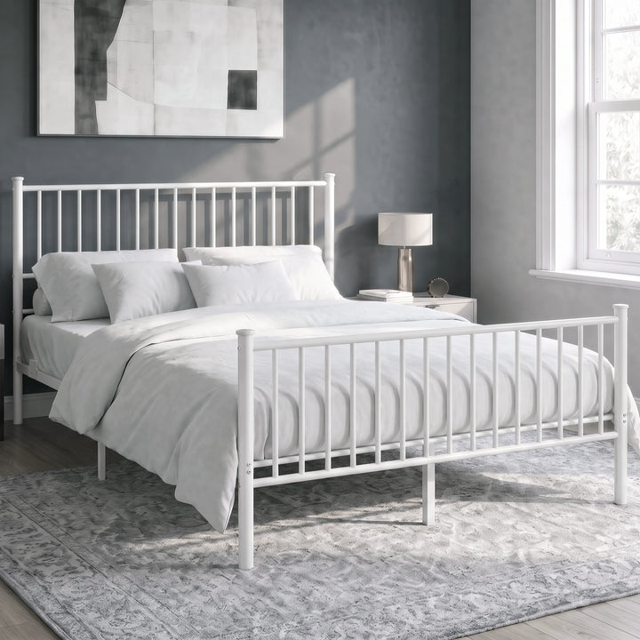 [White | King] Angled view of metal bed with white bedding, bar ends, centre legs, bedside lamps, wall art and bright window.