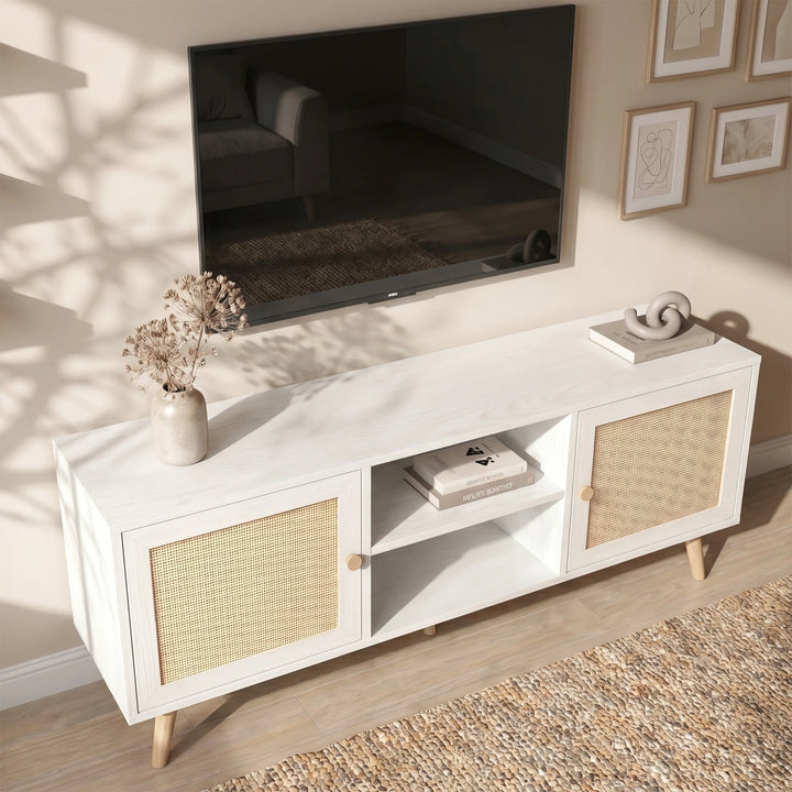 [White] Wovena Rattan TV Unit viewed from above with ceramic vase, books, abstract sculpture, and wall-mounted TV on a textured woven rug