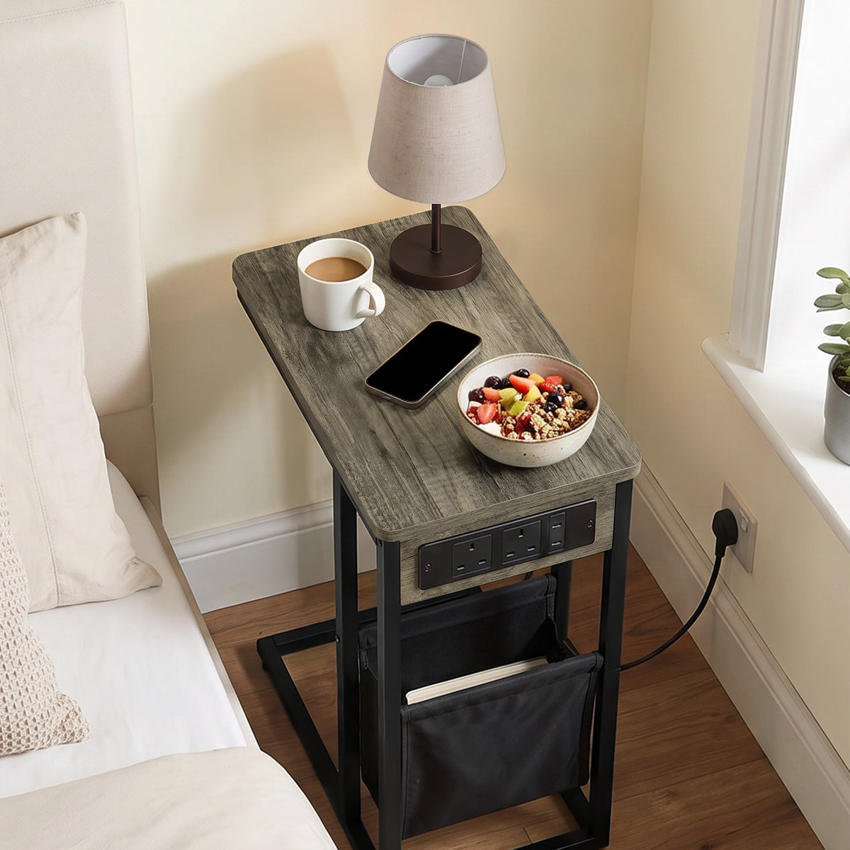 [Wooden Grey]Top view of C-shaped side table with wooden grey-effect top, charging cable, phone and pouch used as bed side table