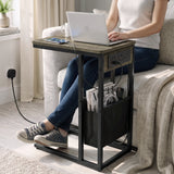 [Wooden Grey]C-shaped side table used for laptop work by sofa with charging station plugged in wall socket and storage pouch
