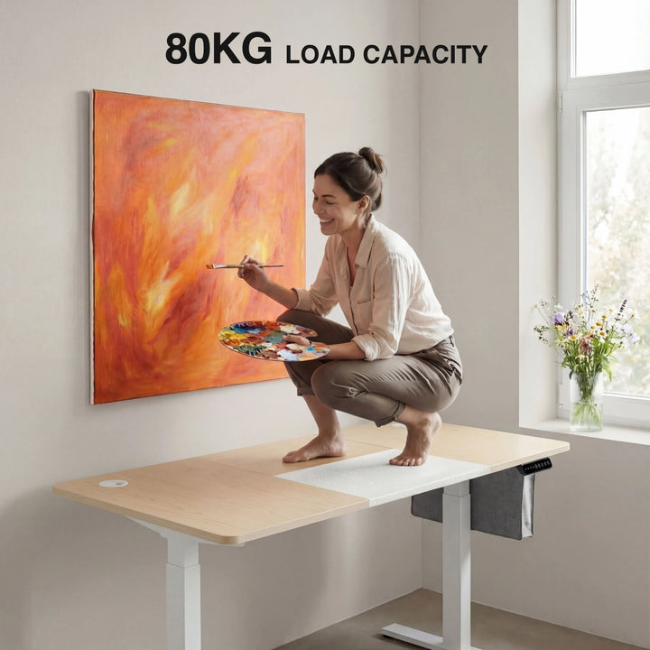 [160cm x 70cm] 80kg load demo on 160x70cm pine standing desk, woman in beige top painting while kneeling on the worktop