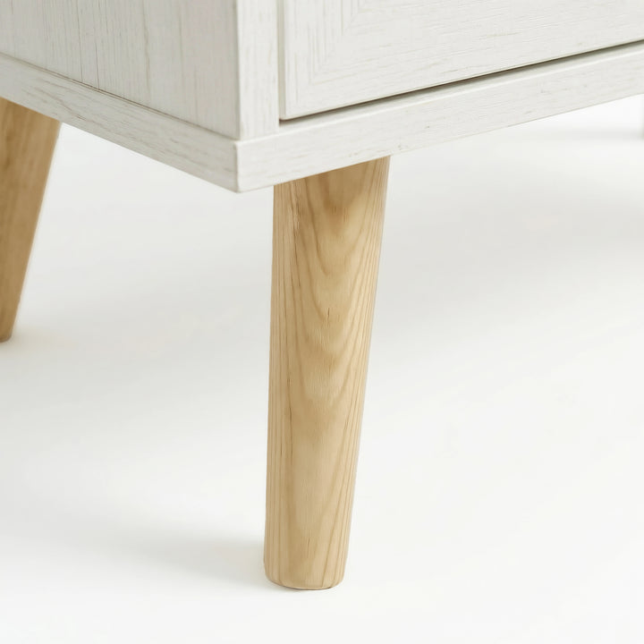 [White] Wovena 3 drawer chest leg detail showing natural pine wood grain and slight taper down to floor