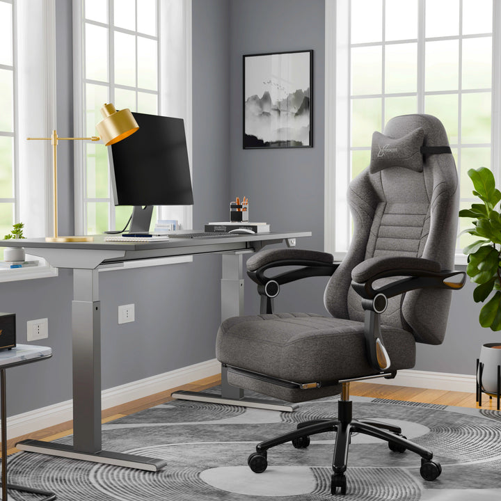 [Grey] A grey office chair in a modern office setting with a desk and lamp.