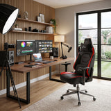 [Black + Red] Xstriker gaming chair with headrest, positioned in a modern home office setup next to a wooden desk, dual computer monitors.